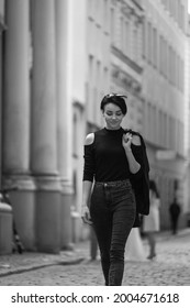 Black And White Portrait Of A Happy Young Girl With Short Hair. Beautiful Woman In Classic Black Clothes Walks Around The City