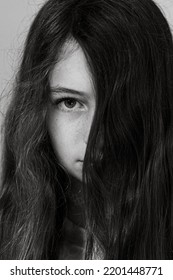 Black And White Portrait Of A Long Haired Preteen With A Fierce Look And One Eye Covered With Hair