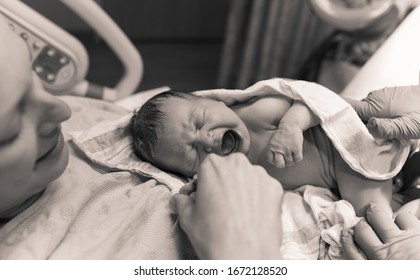 Black And White Portrait Of Mother In Hospital Bed Holding Her New Born Baby In Her Arms For The First Time Moments After Giving Birth, People New Life Concept. 