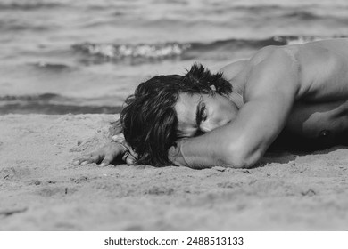  Black and white portrait of a muscular handsome man lying on a sandy beach. - Powered by Shutterstock