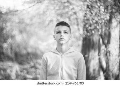 Black And White Portrait Of A Sad Boy Outside In Nature