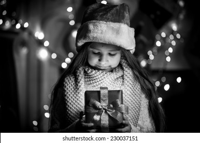 Black And White Portrait Of Smiling Girl Opening Christmas Present Box