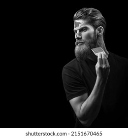 Black and white portrait of stylish man brushing his beard. Bearded man with hair brush. Trendy and stylish beard styling and cut. Copy free space on left