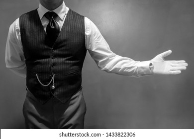 Black and White Portrait of Well Dressed Butler Wearing White Gloves With a Welcoming Gesture. Concept of Service Industry and Professional Hospitality