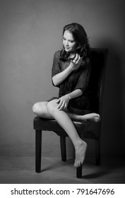 Black And White Portrait Of Woman With See Through Top And Black Underwear Posing On A Black Chair.