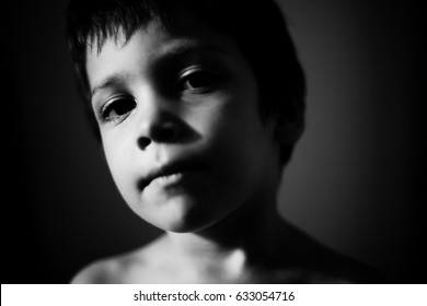 Black And White Portrait Of A Young Boy Looking Serious To The Camera