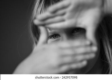 Black And White Portrait Of Young Girl Looking Through Hand As A Director And Cameraman