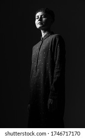 Black And White Portrait Of A Young Hipster Woman, Tranquilly Looking In A Camera, Low Angle Photo On Black Background, Dramatic Light