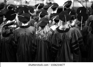 Black and white rear view of graduate students in caps and gowns at a college of law graduation ceremony, with space for text on top
