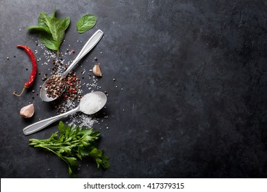 Black, white and red pepper and salt spices in spoon. Mint and parsley herbs. Top view with copy space for your recipe