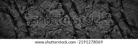 Black white rock texture background. Rough mountain surface with cracks. Close-up. Dark gray stone basalt background for design. Banner. Wide. Long. Panoramic. Website header.