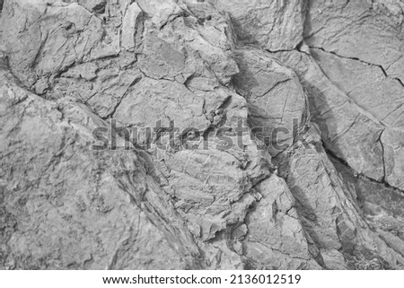 Black white rock texture. Cracked layered mountain surface. Close-up. Gray grungy stone background with space for design.