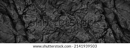 Black white rock texture. Dark gray stone wall background with space for design. Cracked rough mountain surface. Close-up. Wide banner. Panoramic. Granite backdrop. Grunge.