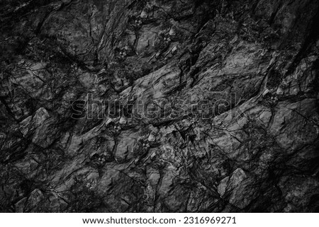 Black white rock texture. Dark stone granite background for design. Rough cracked mountain surface. Close-up. Crumbled.