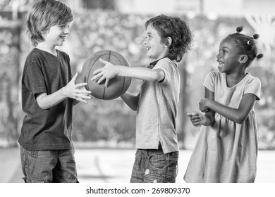 Black And White Scene Of Children Playing Basketball At School.