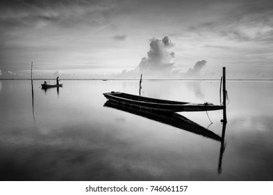 Black & white scenery of traditional fishing boat at Tumpat, Malaysia with fisherman silhouette standing on the boat. Soft focus due to long exposure.  
