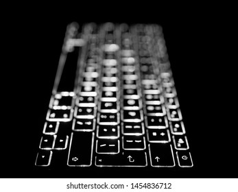 Black and white selective focus close-up on illuminated keys of computer keyboard. Background for technology, programming and journalism concepts and ideas.
