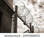 Black and white sepia. Concept. Razor wire. Prison incarceration no escape. Moody bleak sky. Close up detail. Maximum security. Despair loss of freedom punishment consequence. Choices consequences.