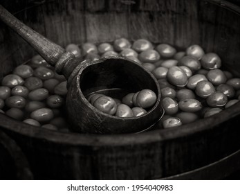 Black and white sepia toned retro image of Wooden barrel of green olives with ladle evoking a Victorian, Edwardian or 1940s style photograph - Powered by Shutterstock