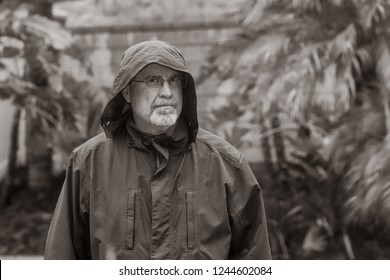 Black And White Serious Older Man Standing In The Rain In Yard Looking Away 