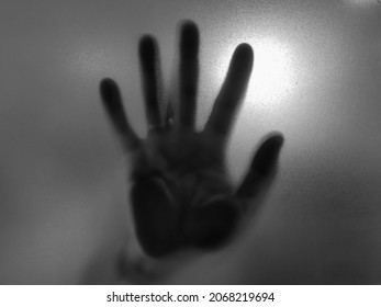 Black And White Shadow Image Of Hand Behind The Frosted Glass Sign Of Scary Fear Bad Haunting Horror.