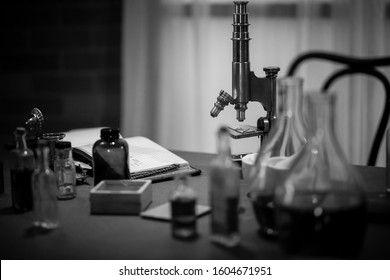 black and white shot of an 1885 scientist labratory. focus on brass microscope