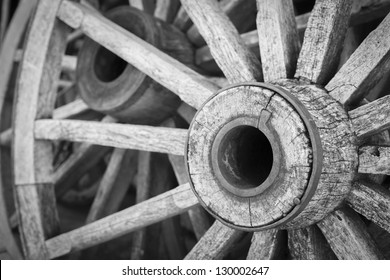 A black and white shot of a bunch of old wood wagon wheels.
