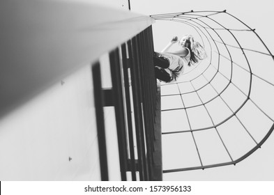 Black And White Shot Of Woman Climbing Ladder On A Roof