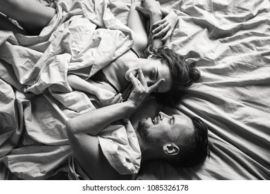 Black And White Shot Of Young Lovely Couple With Tattoos Lie On The Bed In Minimal Style Bedroom. Sexy Couple With Tattoos Kissing On The Bed. Sexy Fitness Man And Woman Playing On The Bed. Tattoes