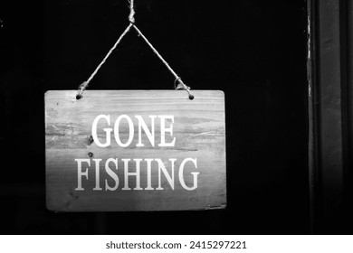 
Black and white sign on a shop door saying that the business is closed because the owner has gone fishing