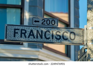 Black and white sign that says Francisco in the historic districts of san francisco california in midday shade. Dense suburban background with visible sun streaks in the downtown city neighborhoods.