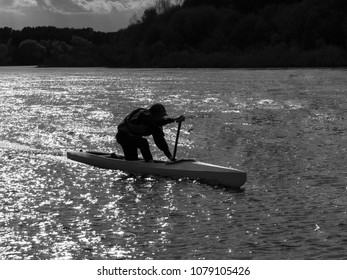 Black And White Silhouette Of A Boy In A Kayak In A Backlight On A River