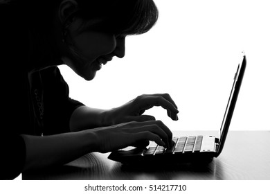 black and white silhouette of a hacker typing on the keyboard of laptop remotely hacking and receiving personal information