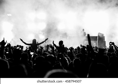 Black and White Silhouette People on Shoulders in Crowd at a Music Festival - Backlit. 
