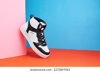 Black and white sneakers on a colored background. Stylish style footwear for advertising a shoe store. Hype sneaker