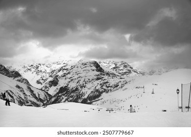 Black and white snowy ski slope with skier and snowboarder in high mountains and cloudy sunlit sky at winter gray day. Ski area Mottolino Fun Mountain, Italian Alps. Livigno, Lombardy, Italy, Europe. - Powered by Shutterstock