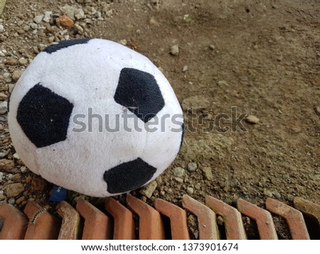 Black and white soccer ball on the ground near the caterpillar. SIde view close up details.