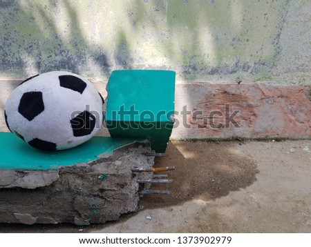 Black and white soccer ball on the blue debris near the wall. Side view close up details.