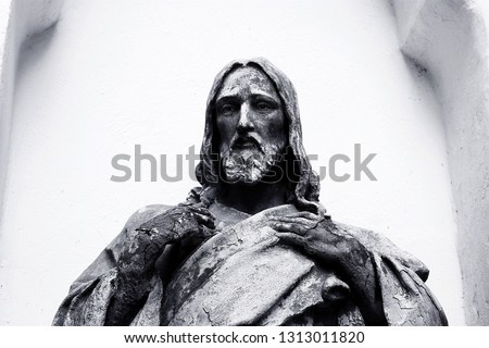 
black and white statue of jesus with cracks in his arms he looks into the distance and presses his arms to his chest