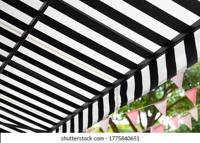 Black And White Striped Awning With Green Garden. 
