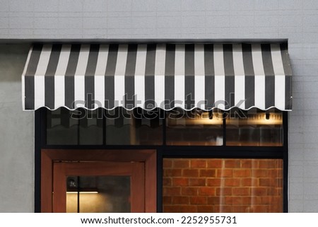 black and white striped awning over the front of store. blind canvas roof shading of the city shop.