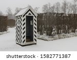 Black and white striped guardhouse in the middle of a snowy park