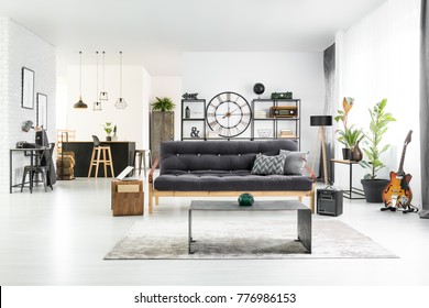 Black And White Stylish Man Cave Interior With Industrial Table, Couch And Home Bar In The Background