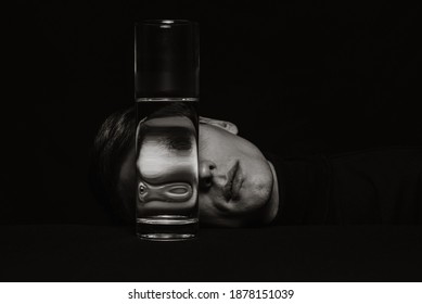 black and white surreal portrait of a man through the glass of a can of water