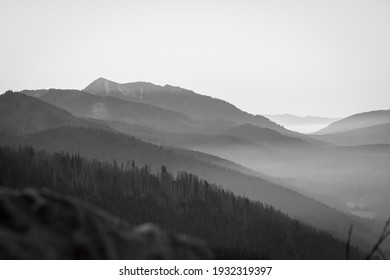 Black and white Tatra Mountain view. Fog is covering the valley, clear sky is illuminating the ridge of the hills. Selective focus on the peak, blurred background.