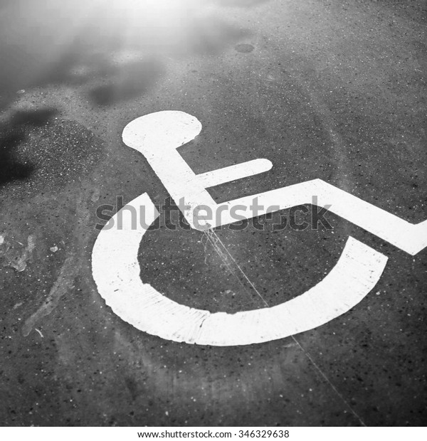Black\
and white view of disabled parking - reserved parking for disabled\
people. The sign painted in white paint on\
asphalt