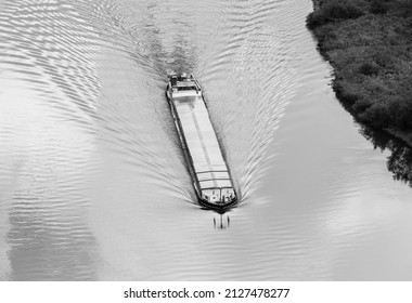 Black and white view down to a boat on the Moselle River in Germany creating a wave pattern. Seen from the Calmont vineyards.