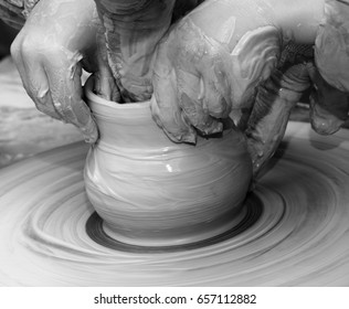 Black and white view on beginner and teacher in process of making clay bowl on pottery wheel. Potters at work.