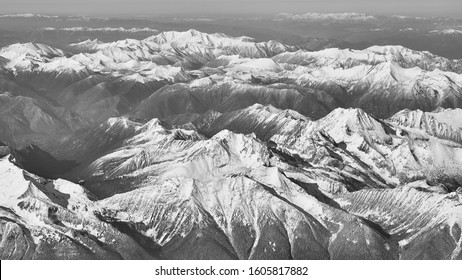 A Black And White View Of The Snow Covered Rocky Mountains Over British Columbia Viewed From A Commercial Plane Flying At 25,000 Feet From Vancouver To Kelowna.