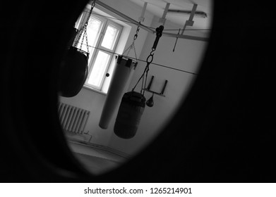 Black And White Vignetted Photo Of Several Punching Bags Hanging In The Gym. No One In The Boxing Club. Empty Club With Punching Bag Of Different Shapes